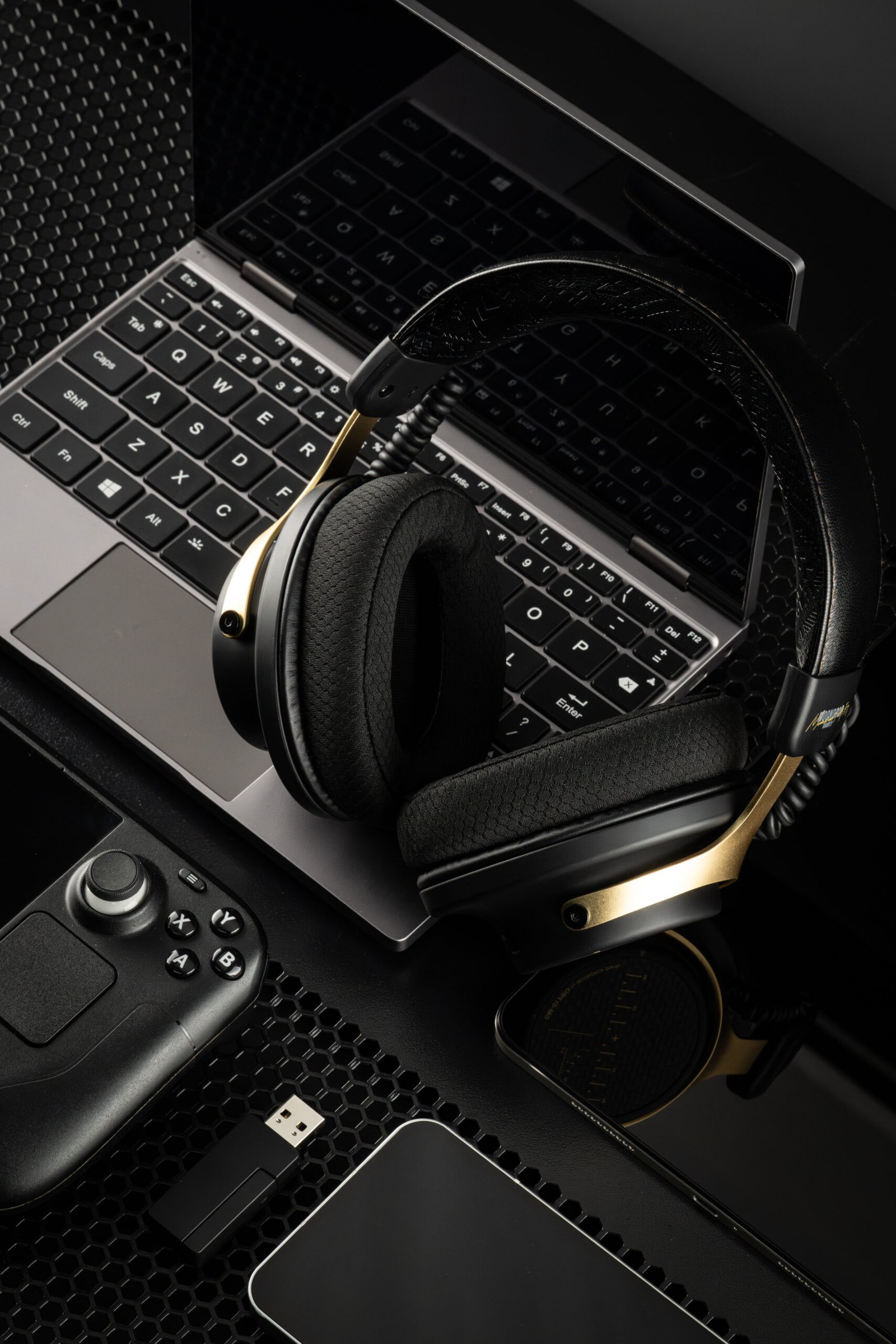 Headset Moondrop Gravity GM-01 PRO Preto sobre um portátil, num setup gaming com comando e recetor USB.